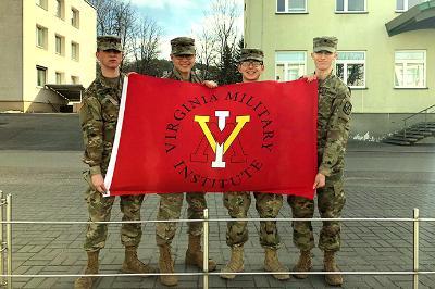 Four cadets hold up a ϲ flag in Lithuania